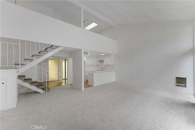 1404 N Tustin Ave Unit H1, Santa Ana, CA 92705 - unfurnished living room with light colored carpet, beamed ceiling, high vaulted ceiling, and stairs