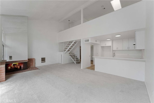 1404 N Tustin Ave Unit H1, Santa Ana, CA 92705 - unfurnished living room featuring light carpet, a brick fireplace, stairway, and a high ceiling