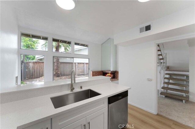 1404 N Tustin Ave Unit H1, Santa Ana, CA 92705 - kitchen with stainless steel dishwasher, light countertops, white cabinetry, and light wood-style flooring