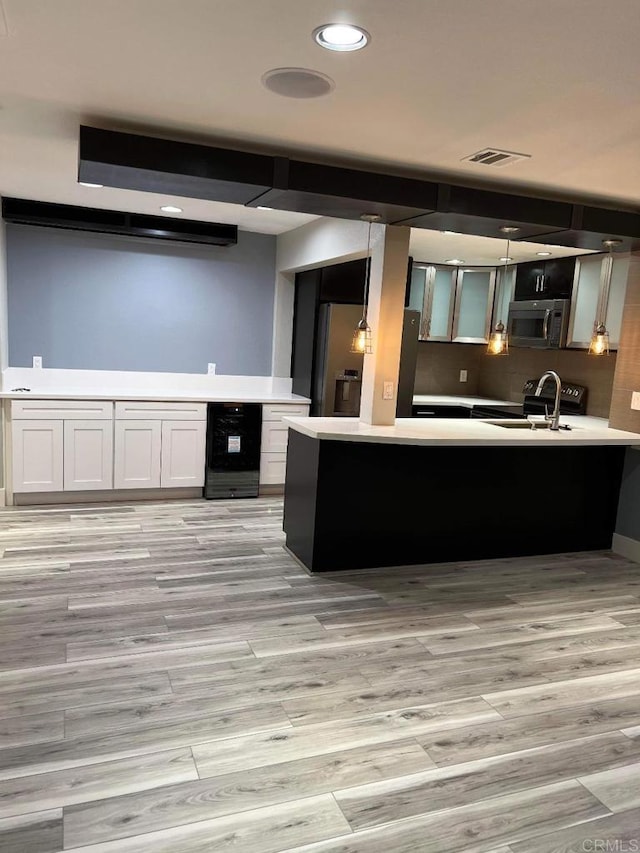 3078 Broadway Unit 107, San Diego, CA 92102 - kitchen with stainless steel microwave, light wood-type flooring, a peninsula, light countertops, and electric range