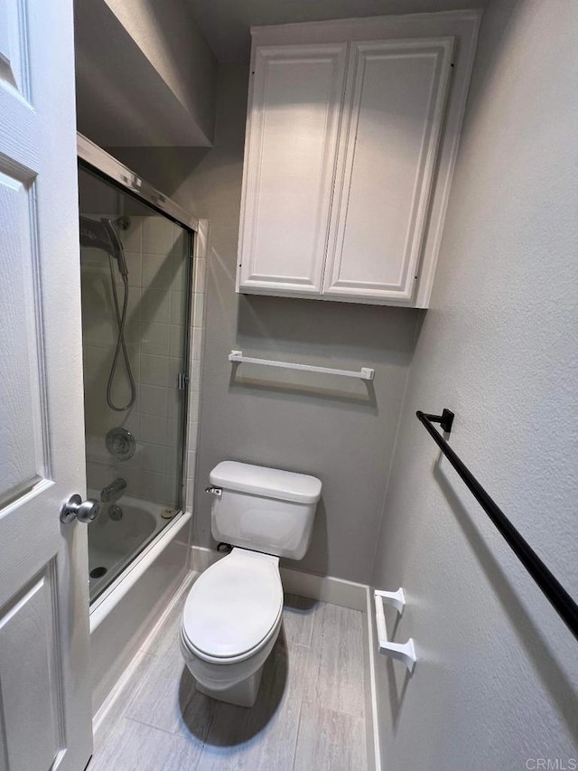 3078 Broadway Unit 107, San Diego, CA 92102 - bathroom featuring toilet, shower / bath combination with glass door, baseboards, and wood finished floors