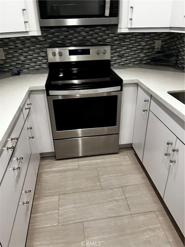 6330 Genesee Ave Unit 103, San Diego, CA 92122 - kitchen featuring stainless steel range with electric cooktop, white cabinets, light countertops, and tasteful backsplash