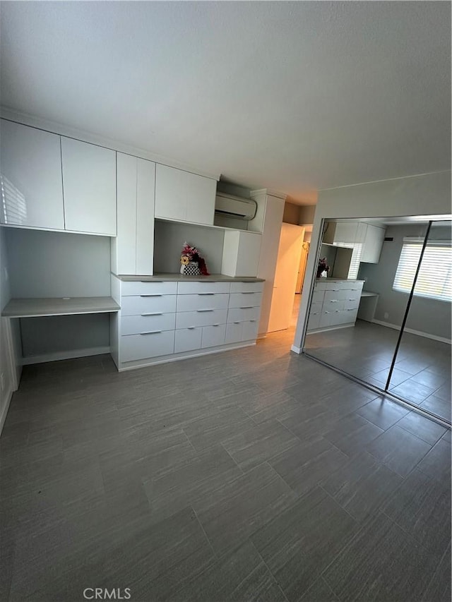 6330 Genesee Ave Unit 103, San Diego, CA 92122 - unfurnished bedroom featuring a wall unit AC, dark colored carpet, and a closet