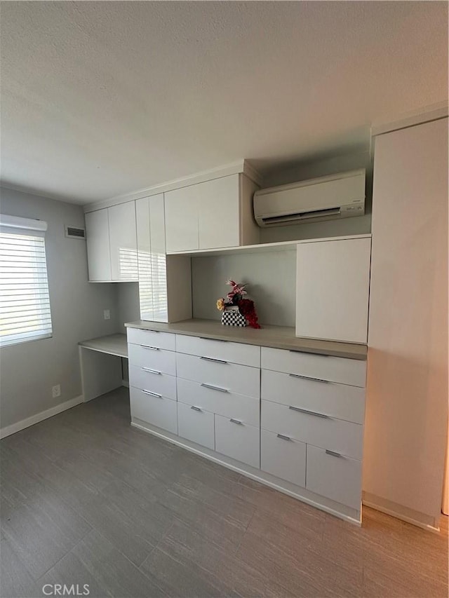 6330 Genesee Ave Unit 103, San Diego, CA 92122 - kitchen with a wall mounted AC, modern cabinets, white cabinetry, a textured ceiling, and light countertops