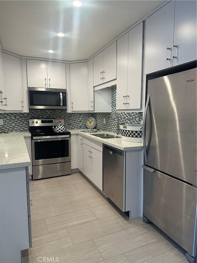 6330 Genesee Ave Unit 103, San Diego, CA 92122 - kitchen featuring appliances with stainless steel finishes, backsplash, white cabinetry, and light stone counters