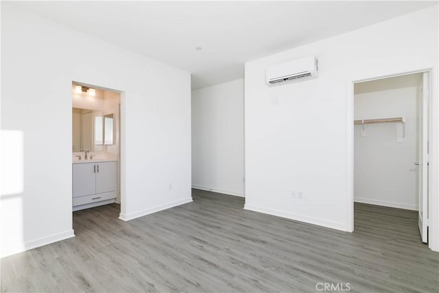 667 Limoncello Ln, Covina, CA 91723 - unfurnished bedroom featuring a wall unit AC, wood finished floors, a walk in closet, baseboards, and a sink