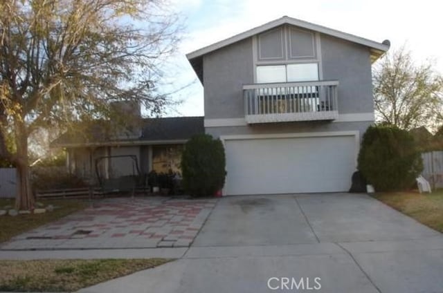 943 W Valencia St, Rialto, CA 92376 - view of front facade featuring a balcony, driveway, an attached garage, and stucco siding