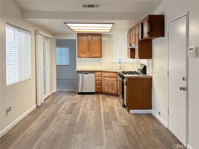 13941 Parkwood Dr, Fontana, CA 92337 - kitchen featuring appliances with stainless steel finishes, decorative backsplash, wood finished floors, and brown cabinets