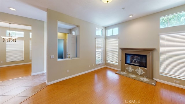 4312 Waterside Ln, Oxnard, CA 93035 - unfurnished living room with a chandelier, a glass covered fireplace, wood finished floors, baseboards, and recessed lighting