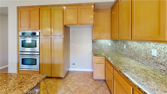 4312 Waterside Ln, Oxnard, CA 93035 - kitchen with stainless steel double oven, decorative backsplash, light stone countertops, and baseboards