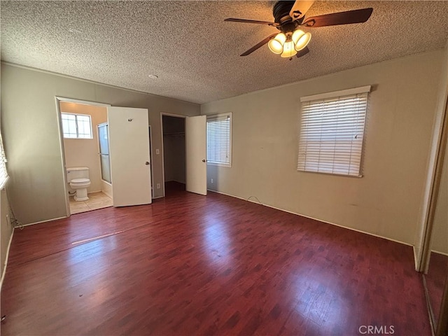 1434 W 92nd St, Los Angeles, CA 90047 - unfurnished bedroom with dark wood-style floors, a textured ceiling, multiple windows, ensuite bath, and a closet