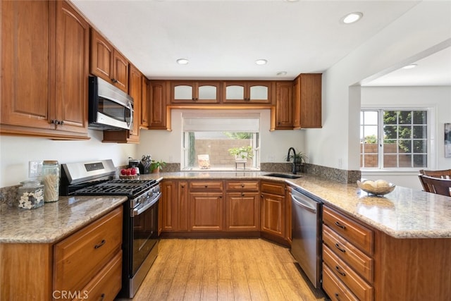 1188 Old Hickory Rd, Corona, CA 92882 - kitchen featuring appliances with stainless steel finishes, light stone countertops, a peninsula, brown cabinets, and light wood-style flooring