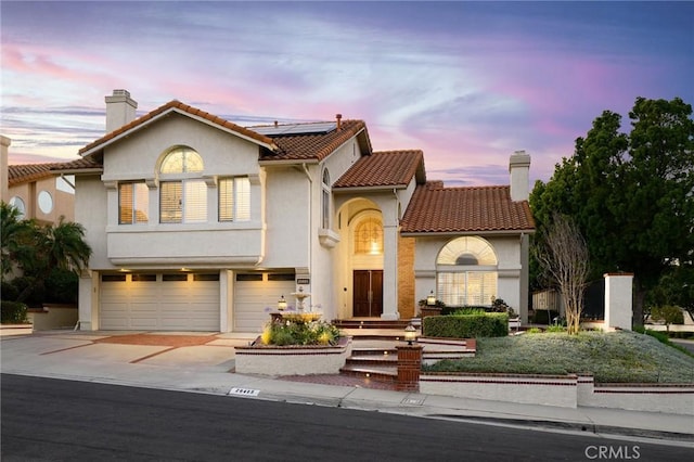 20485 Via Canarias, Yorba Linda, CA 92887 - mediterranean / spanish-style home with an attached garage, solar panels, driveway, stucco siding, and a chimney