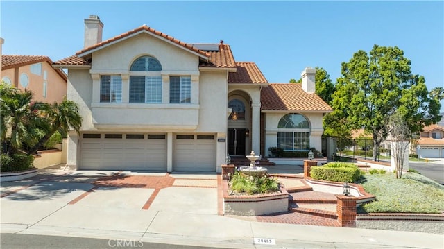20485 Via Canarias, Yorba Linda, CA 92887 - mediterranean / spanish-style home featuring a chimney, a garage, driveway, stucco siding, and solar panels
