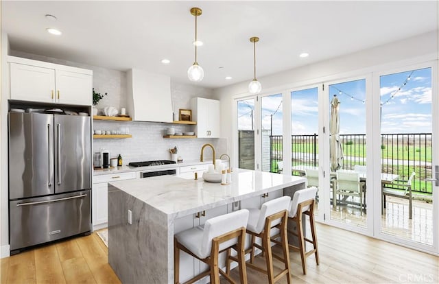 2294 Pacific Ave, Costa Mesa, CA 92627 - kitchen with high end refrigerator, open shelves, light wood finished floors, white cabinets, and tasteful backsplash