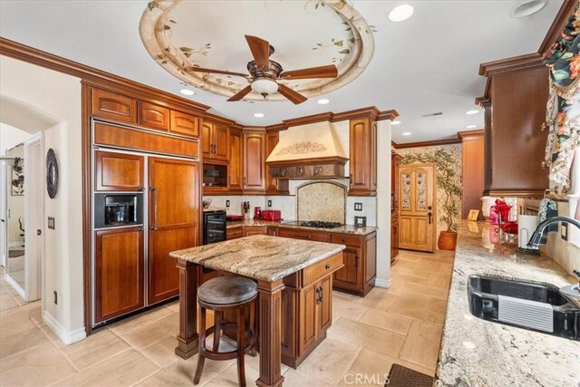 1506 Bergman Ct, Brea, CA 92821 - kitchen featuring paneled built in fridge, custom range hood, ceiling fan, black stovetop, and light stone countertops