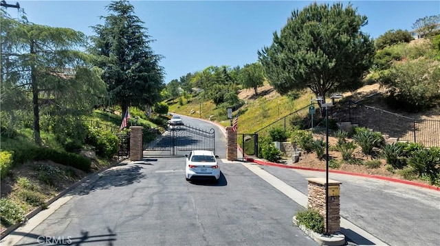 13909 Mountain View Pl, Sylmar, CA 91342 - view of asphalt road with a gate, curbs, and a gated entry