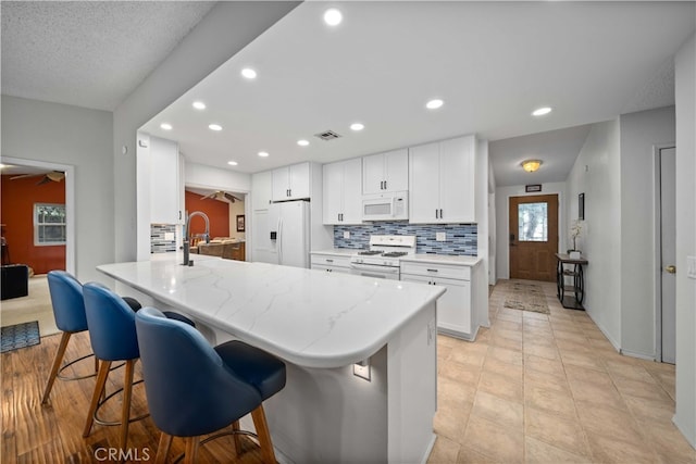 802 Duval St, La Verne, CA 91750 - kitchen featuring white appliances, backsplash, a breakfast bar, a peninsula, and a ceiling fan