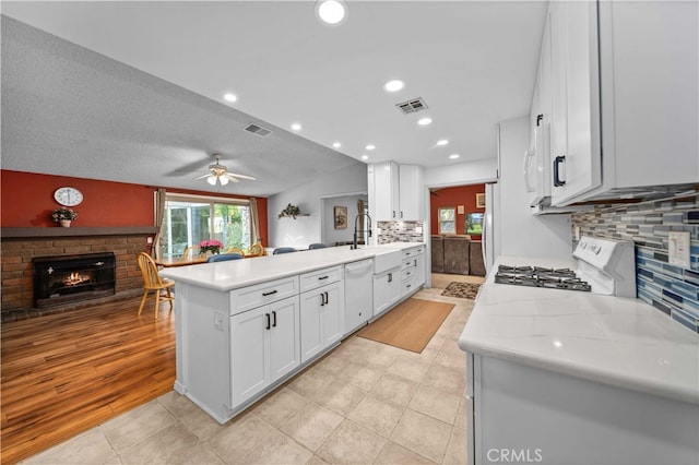 802 Duval St, La Verne, CA 91750 - kitchen featuring white appliances, a peninsula, a brick fireplace, light countertops, and open floor plan