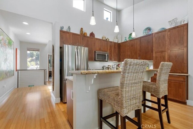 223 San Miguel St, Avila Beach, CA 93424 - kitchen featuring stainless steel appliances, light wood-type flooring, hanging light fixtures, a kitchen breakfast bar, and baseboards