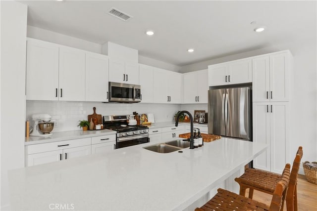 3590 E Peckham Paseo Unit 6, Ontario, CA 91761 - kitchen featuring appliances with stainless steel finishes, a kitchen breakfast bar, white cabinets, backsplash, and recessed lighting