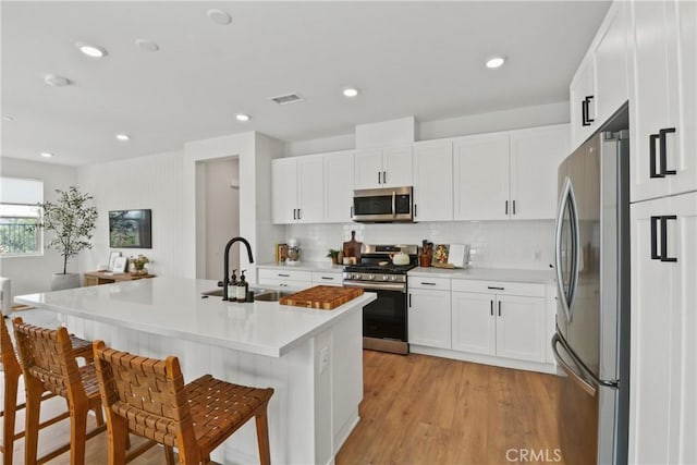 3590 E Peckham Paseo Unit 6, Ontario, CA 91761 - kitchen with stainless steel appliances, a breakfast bar, backsplash, white cabinetry, and recessed lighting