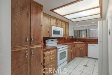 965 Morro Ave Unit D, Morro Bay, CA 93442 - kitchen featuring white appliances, brown cabinetry, a sink, and light tile patterned floors