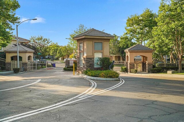 8749 Fairoaks Ct, Rancho Cucamonga, CA 91730 - view of asphalt street with a gate, street lights, a gated entry, and curbs