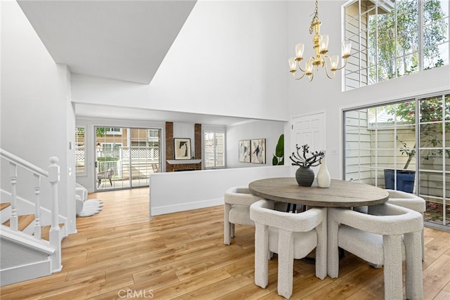 431 Cranston Ct Unit 102, Long Beach, CA 90803 - dining room with a chandelier, light wood-style floors, a towering ceiling, stairway, and a fireplace