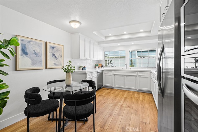 431 Cranston Ct Unit 102, Long Beach, CA 90803 - kitchen featuring stainless steel appliances, light wood finished floors, white cabinets, light countertops, and a raised ceiling