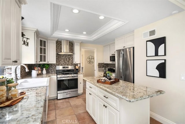 27692 Motherlode Ct, Laguna Niguel, CA 92677 - kitchen with stainless steel appliances, wall chimney exhaust hood, a raised ceiling, decorative backsplash, and a kitchen island
