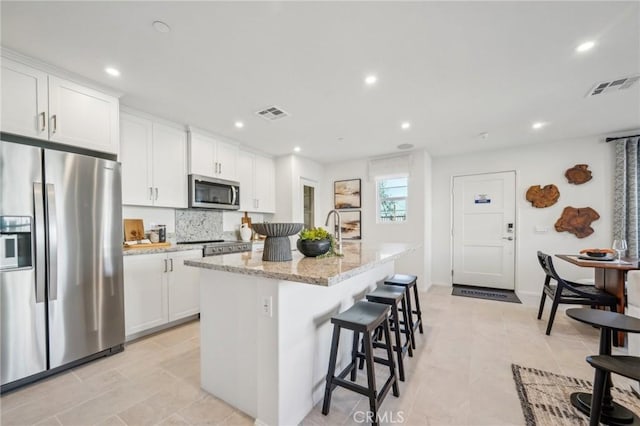 16183 Lumia Way, Fontana, CA 92336 - kitchen with appliances with stainless steel finishes, a kitchen island with sink, recessed lighting, and white cabinets