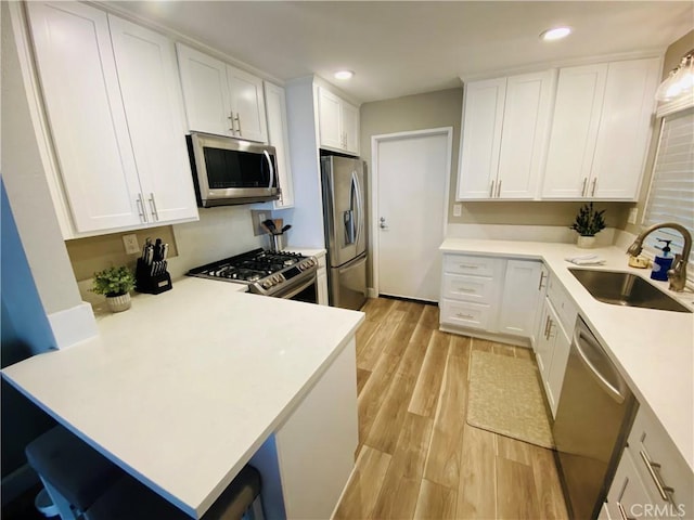 1225 Lima Cir Unit 18, Placentia, CA 92870 - kitchen with stainless steel appliances, light wood-style floors, a peninsula, white cabinetry, and light countertops