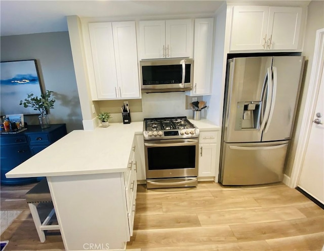 1225 Lima Cir Unit 18, Placentia, CA 92870 - kitchen with appliances with stainless steel finishes, white cabinetry, light countertops, light wood-style flooring, and a peninsula