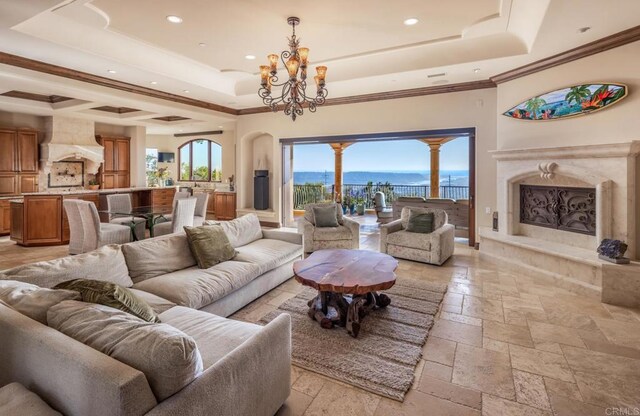 7133 Obelisco Cir, Carlsbad, CA 92009 - living room featuring a tray ceiling, stone tile flooring, a chandelier, recessed lighting, and crown molding