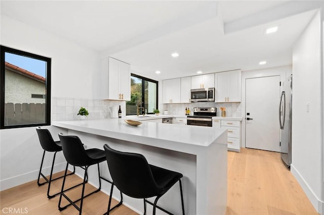2959 Butler St, Oceanside, CA 92054 - kitchen with stainless steel appliances, a peninsula, a breakfast bar, light countertops, and decorative backsplash