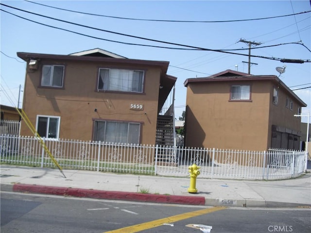 5659 Quinn St, Bell Gardens, CA 90201 - view of front of home with stucco siding, a fenced front yard, and stairs