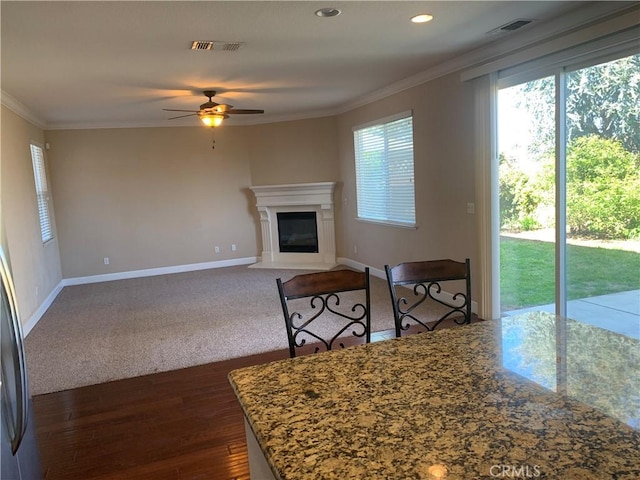 538 Burnt Ranch Way, Chico, CA 95973 - unfurnished living room featuring crown molding, plenty of natural light, a ceiling fan, dark wood-style floors, and a glass covered fireplace