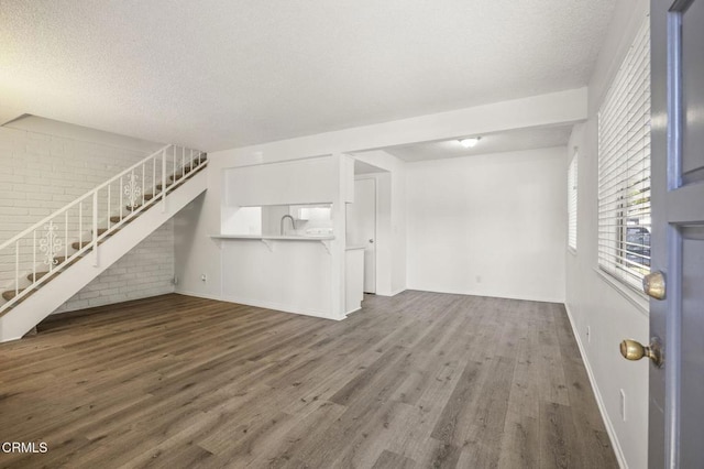 2692 Anchor Ave, Port Hueneme, CA 93041 - unfurnished living room featuring stairway, wood finished floors, brick wall, and a textured ceiling