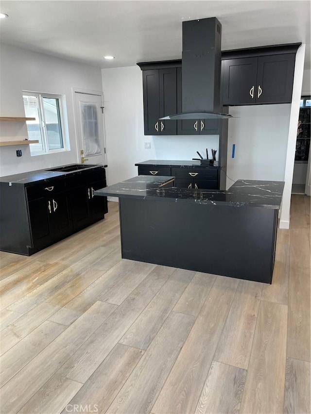 1082 Lewis Ave, Long Beach, CA 90813 - kitchen featuring wall chimney exhaust hood, dark cabinetry, light wood-style flooring, recessed lighting, and a center island