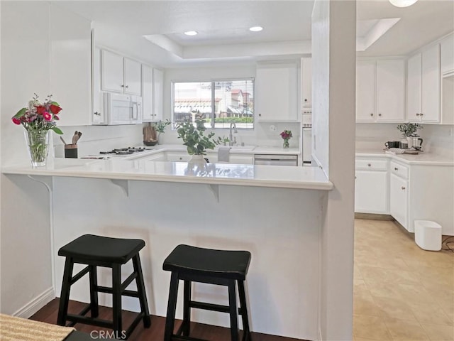 5924 S Pacific Coast Hwy Unit 22, Redondo Beach, CA 90277 - kitchen featuring a sink, a tray ceiling, white appliances, white cabinets, and recessed lighting