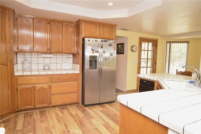 19180 Osceola Rd, Apple Valley, CA 92307 - kitchen with stainless steel refrigerator with ice dispenser, tile counters, a sink, light wood-style flooring, and tasteful backsplash