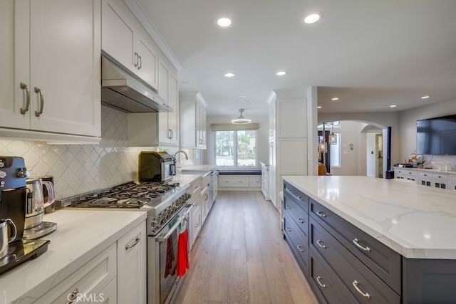 627 7th St, Huntington Beach, CA 92648 - kitchen with appliances with stainless steel finishes, under cabinet range hood, white cabinets, light wood-style flooring, and arched walkways