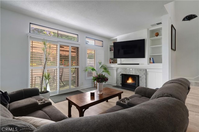 28215 Paseo El Siena Unit 46, Laguna Niguel, CA 92677 - living room with a tiled fireplace, built in shelves, wood finished floors, and a textured ceiling