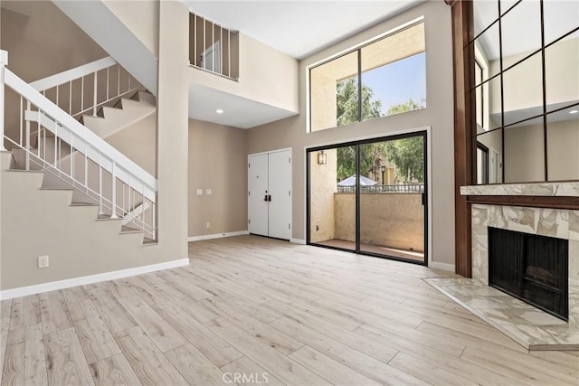 26322 W Bravo Ln, Calabasas, CA 91302 - unfurnished living room featuring a high ceiling, stairway, a premium fireplace, wood finished floors, and baseboards