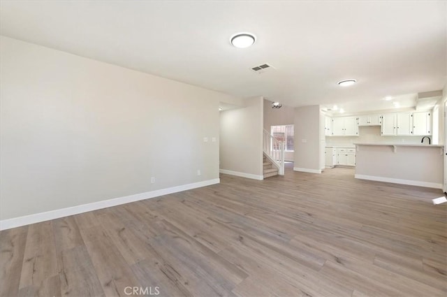 27541 Vanilla Ct, Menifee, CA 92585 - unfurnished living room featuring light wood-style flooring, baseboards, and stairway