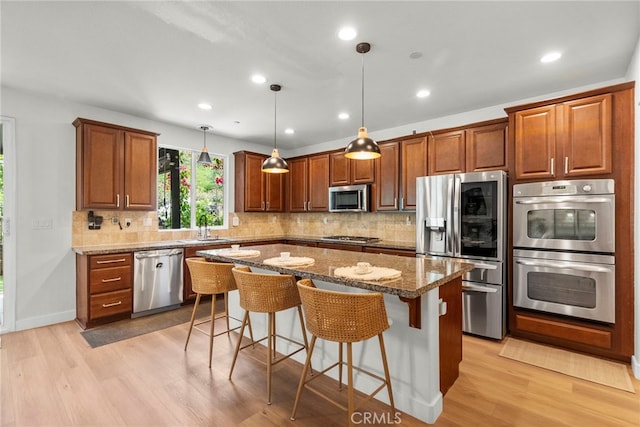 28321 Esplanada Dr, Valencia, CA 91354 - kitchen featuring appliances with stainless steel finishes, a kitchen island, a sink, light wood-type flooring, and stone counters