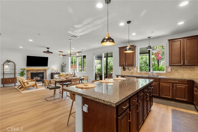 28321 Esplanada Dr, Valencia, CA 91354 - kitchen featuring light wood-style flooring, a stone fireplace, tasteful backsplash, a center island, and open floor plan