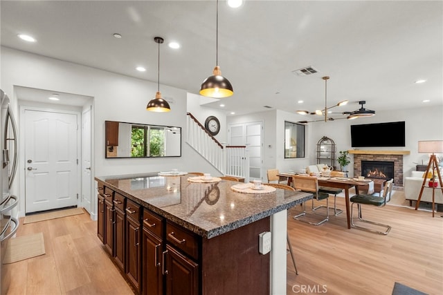 28321 Esplanada Dr, Valencia, CA 91354 - kitchen featuring light wood finished floors, a stone fireplace, a center island, recessed lighting, and dark stone countertops