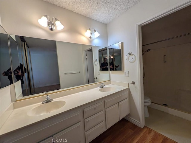 1266 Tarryglen Ln, San Dimas, CA 91773 - bathroom with wood finished floors, a textured ceiling, double vanity, a shower, and toilet